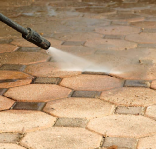A pressure washer cleaning a hexagonal stone-paved surface. The water jet, a key tool in St. Charles remodeling, is removing dirt and grime from the surface, leaving it looking clean and renewed.
